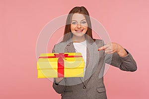 Portrait of joyful elegant businesswoman in suit jacket pointing at present, celebrating anniversary photo