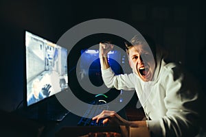 Portrait of a joyful gamer at night in a room at home, winning the game, looking into the camera with a happy face. Portrait of a