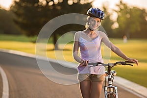 Portrait of joyful girl with bicycle outdoors.