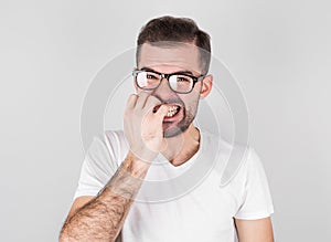 Portrait of joyful handsome bearded guy clenches teeth, blinks eye, bites nails over gray background photo