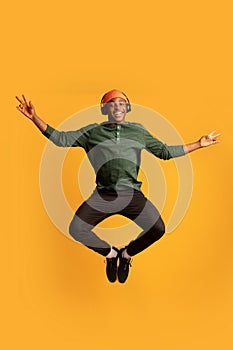 Portrait Of Joyful Happy Black Guy In Wireless Headphones Jumping In Air