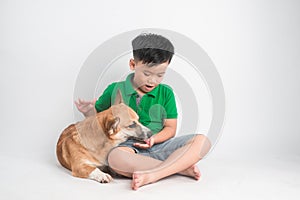 Portrait of a joyful little boy having fun with welsh corgi dog on the floor at studio