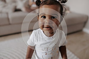 Portrait of joyful mixed race toddler girl in room
