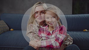 Portrait of joyful mom and daughter hugging indoor