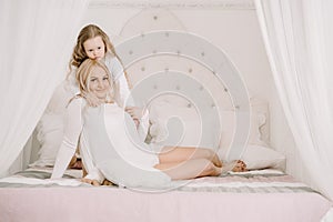 Portrait of a joyful mother and her daughter having relax and joy at the bed on white background