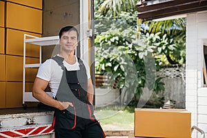 Portrait of a joyful mover working unloading boxes from a truck into a new home