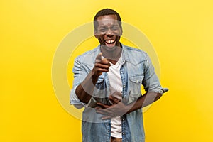 Portrait of joyful positive man laughing out loud. indoor studio shot isolated on yellow background