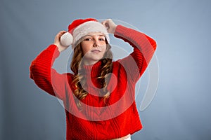 Portrait of joyful pretty woman in red santa claus hat laughing  on gray background. Beautiful girl looking happy and