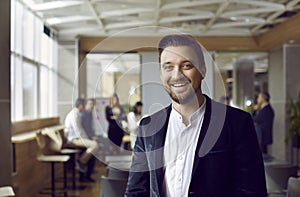 Portrait of joyful satisfied businessman on blurred background of people in office.