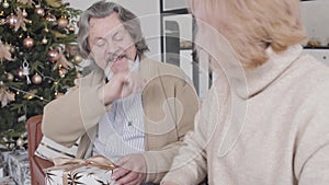 Portrait of joyful senior man giving high five to blond mature woman and talking. Cheerful elegant husband preparing