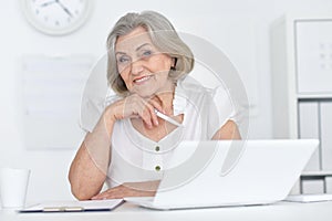 Portrait of joyful senior woman with laptop at home