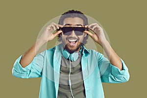 Portrait of joyful smiling Indian man wearing casual clothes, headphones and sunglasses