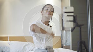 Portrait of joyful teenager recording video for social media dancing in bedroom at home. Cheerful African American