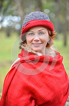 Portrait of the joyful woman in a red stole and a hat. Close up