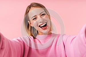 Portrait of joyful woman smiling at camera while taking selfie photo