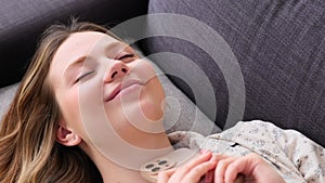 Portrait Of A Joyful Woman Using Phone And Relaxing On Sofa At Home