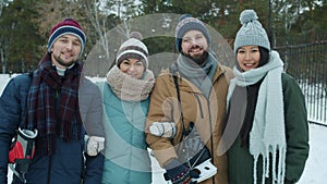Portrait of joyful young people male and female standing outdoors in park in winter with ice-skates