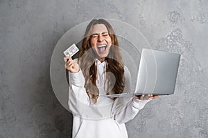 Portrait of a joyful young woman using laptop computer