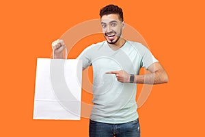 Portrait of joyous buyer, brunette man pointing at packages, shopping bags. indoor studio shot isolated on orange background