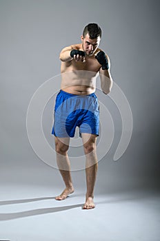 Portrait of kickboxer on a gray background.