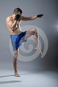Portrait of kickboxer on a gray background.