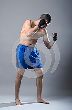 Portrait of kickboxer on a gray background.