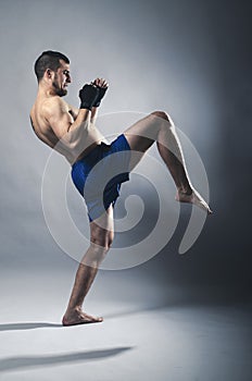 Portrait of kickboxer on a gray background.