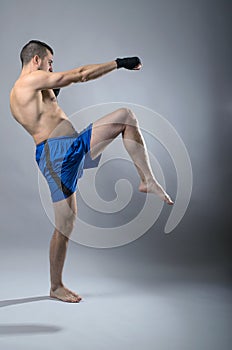 Portrait of kickboxer on a gray background.