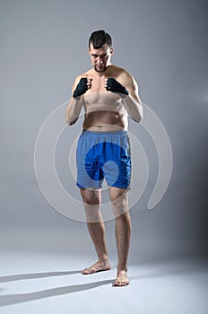 Portrait of kickboxer on a gray background.