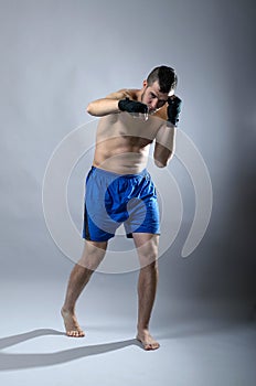 Portrait of kickboxer on a gray background.