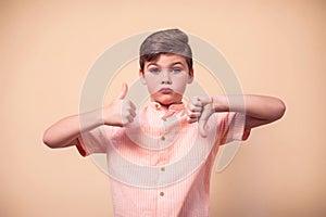 A portrait of kid boy showing thumb up and down gesture. Children and emotions concept