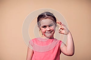 A portrait of kid girl showing okay sign. Children and emotions concept