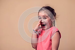 A portrait of kid girl whispering a secret. Children and emotions concept