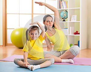 Portrait of kid and mother doing physical exercise at home