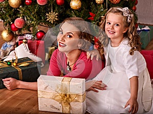 Portrait of kid with mother near Christmas tree and gifts.