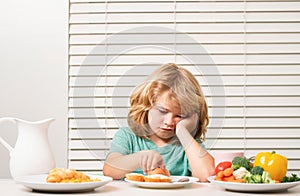 Portrait of kid with no appetite. Concept of loss of appetite. Child eats organic food. Healthy vegetables with vitamins