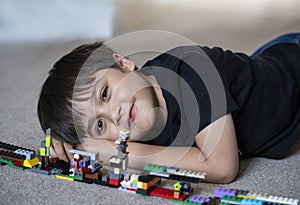 Portrait kid playing plastic blocks, Happy Child boy lying on carpet floor  bluiding his colouful blocks toys, Young boy with