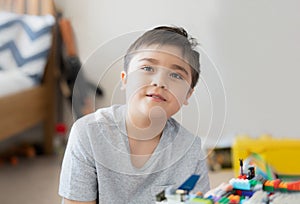 Portrait kid playing plastic blocks, Happy Child relaxing sitting on carpet building his colourful blocks toys in bedroom, Young
