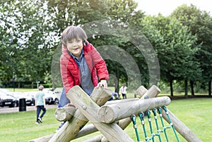 Portrait kid sitting on wooden climbing frame in the park, Child enjoying activity in a climbing adventure park on summer sunny da