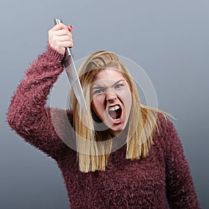 Portrait of killer woman with knife against gray background photo