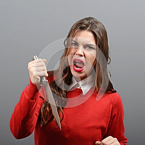 Portrait of killer woman with knife against gray background photo