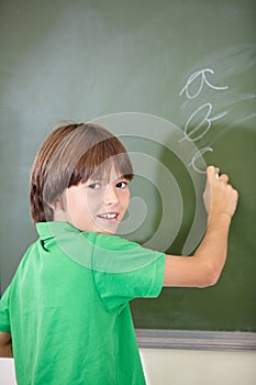 Portrait, knowledge and boy drawing on a chalkboard for child development, creativity and art for learning. Academic