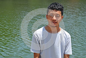 Portrait of a Ladakhi North Indian young guy looking at camera and standing beside of lake with copy space