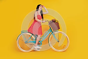 Portrait of lady ride bicycle look empty space wear dotted red short dress footwear on yellow background