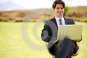 Portrait, laptop and businessman on chair in nature, typing email online on pc or remote work outdoor on mockup space