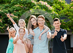 Portrait of large family of six standing and holding thumbs up