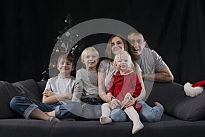 Portrait of large friendly family on Christmas Eve. Mom dad and three children at home on Christmas tree background