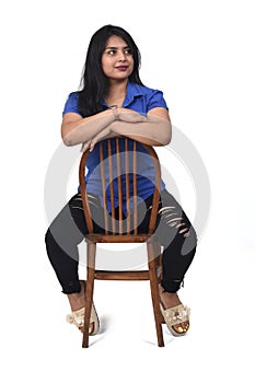 Portrait of a latein woman  sitting on a chair in white background, look side