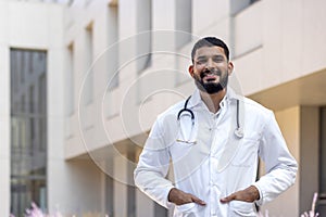 Portrait of a Latin American male doctor, nurse, veterinarian standing outside the clinic on the street in a white coat