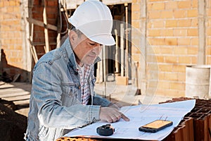 Portrait of latin construction engineer with white hard hat looking at blueprint